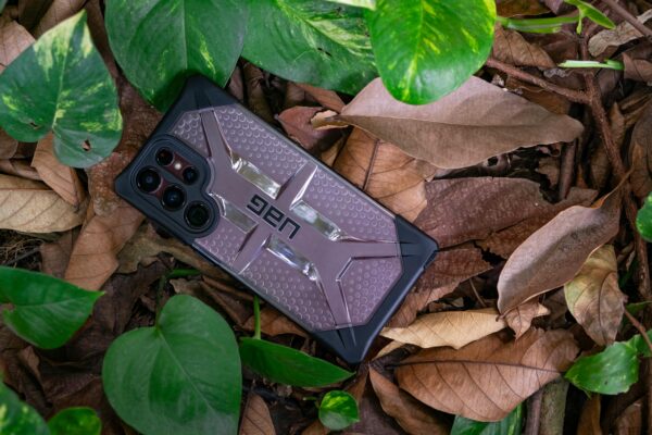 High-quality Urban Armor Gear phone case on a forest floor in Ho Chi Minh City, surrounded by leaves.